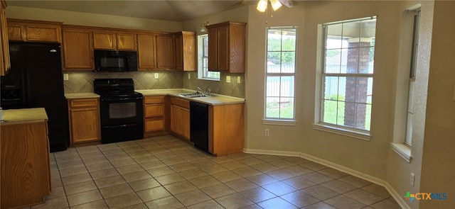 kitchen with plenty of natural light, black appliances, sink, and tasteful backsplash