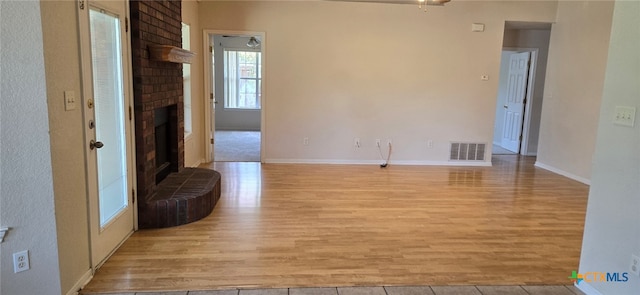 unfurnished living room featuring a fireplace, light hardwood / wood-style floors, and ceiling fan