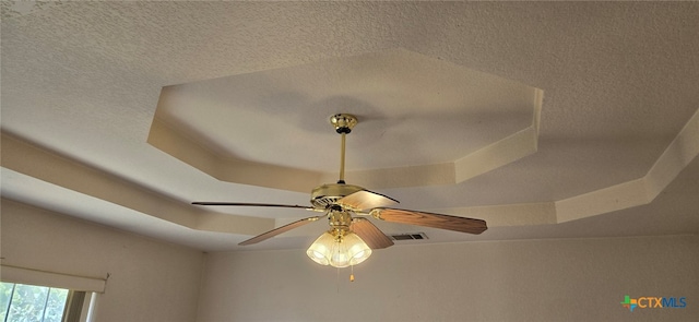 interior details with ceiling fan, a textured ceiling, and a raised ceiling