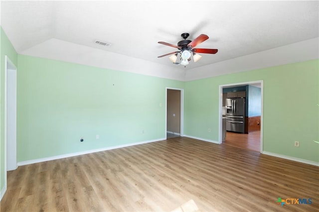 empty room featuring a ceiling fan, wood finished floors, visible vents, and baseboards