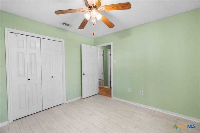 unfurnished bedroom featuring light wood finished floors, a closet, visible vents, ceiling fan, and baseboards