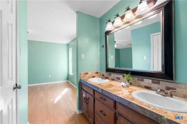 bathroom featuring double vanity, wood finished floors, a sink, and decorative backsplash