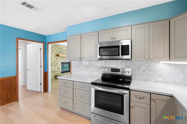 kitchen featuring appliances with stainless steel finishes, gray cabinets, a textured ceiling, light countertops, and light wood-type flooring