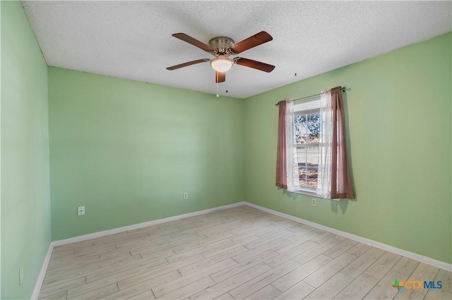 spare room with light wood-style floors, a textured ceiling, baseboards, and a ceiling fan