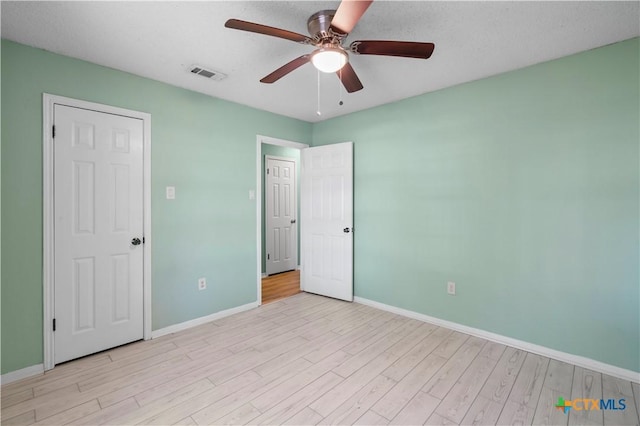 unfurnished bedroom with light wood finished floors, baseboards, visible vents, and ceiling fan