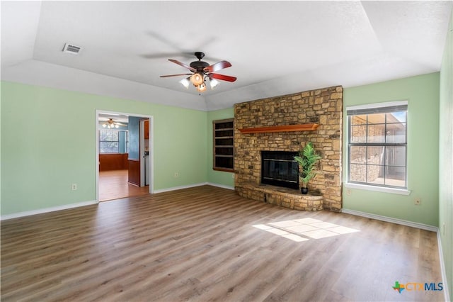 unfurnished living room featuring a large fireplace, baseboards, and wood finished floors