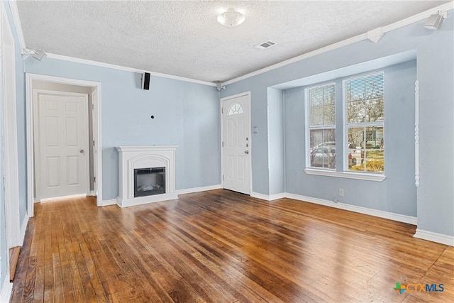 unfurnished living room with hardwood / wood-style flooring, ornamental molding, and a textured ceiling