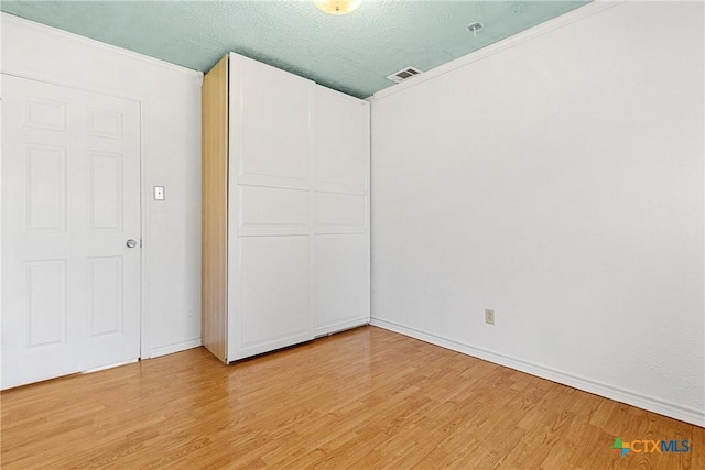 unfurnished bedroom with a closet, a textured ceiling, and light wood-type flooring