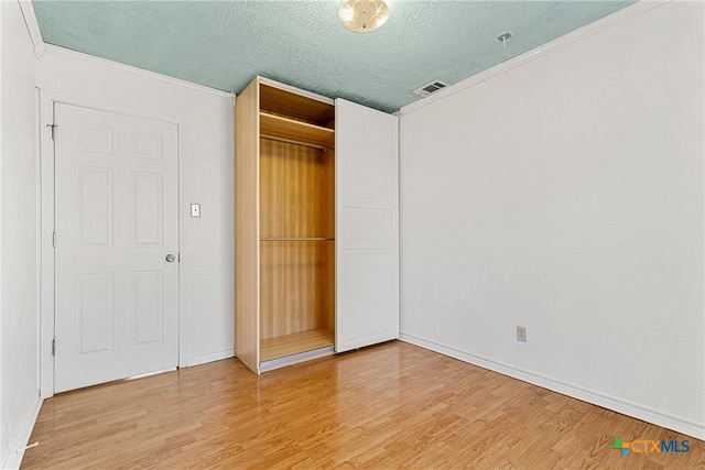 unfurnished bedroom with wood-type flooring, a closet, and a textured ceiling