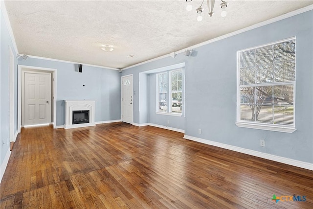 unfurnished living room featuring an inviting chandelier, ornamental molding, wood-type flooring, and a textured ceiling