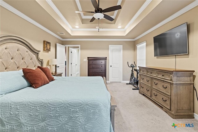 carpeted bedroom with ceiling fan, a tray ceiling, and crown molding