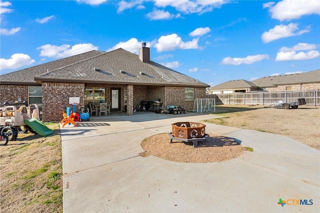 back of property with an outdoor fire pit, a patio, and a playground