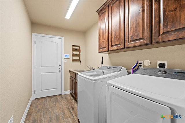 clothes washing area with washer and dryer, cabinets, hardwood / wood-style floors, and sink