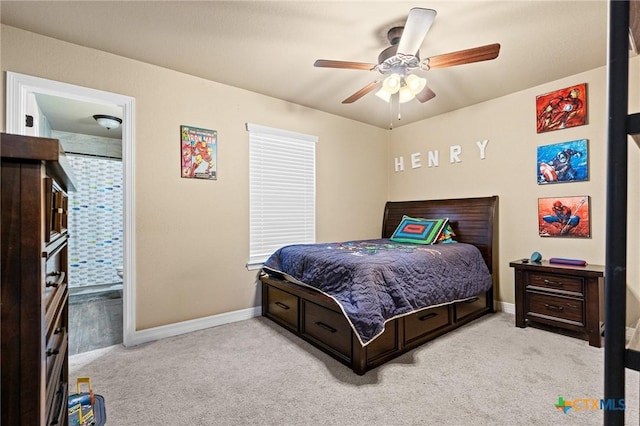 bedroom with ceiling fan, light colored carpet, and ensuite bath