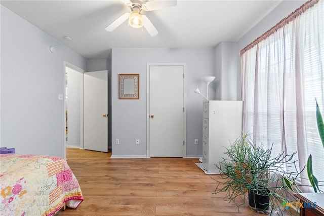 bedroom with light wood-style flooring, baseboards, and ceiling fan