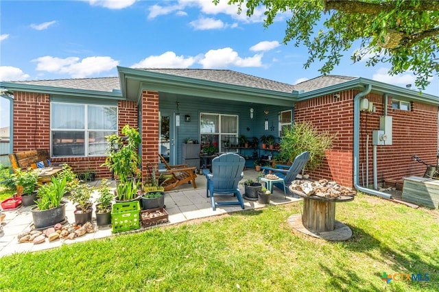 rear view of house with a patio area, brick siding, and a yard