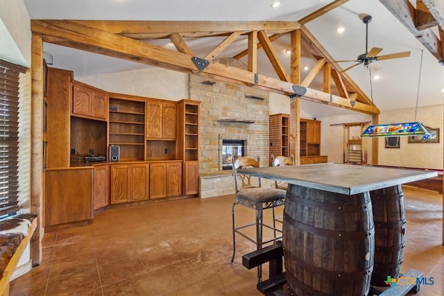 kitchen featuring beamed ceiling, ceiling fan, a fireplace, and high vaulted ceiling