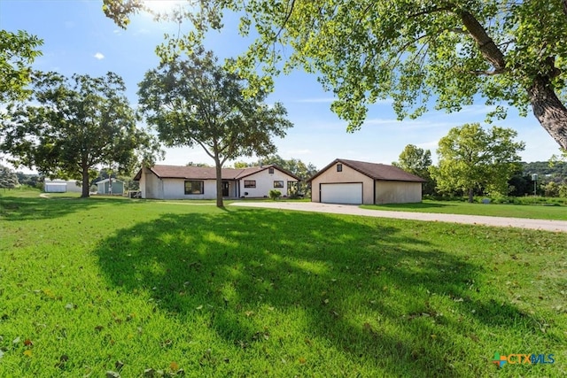 ranch-style home with a garage, an outbuilding, and a front yard