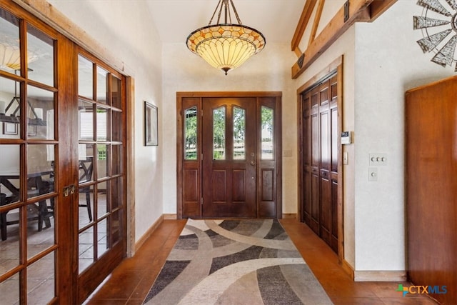 foyer featuring french doors, dark tile patterned floors, and vaulted ceiling