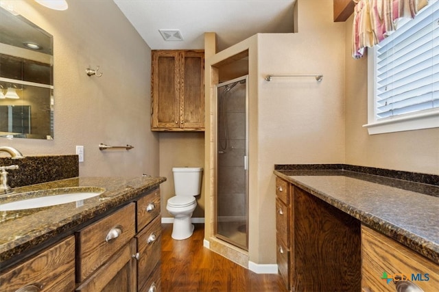 bathroom featuring hardwood / wood-style flooring, vanity, toilet, and walk in shower