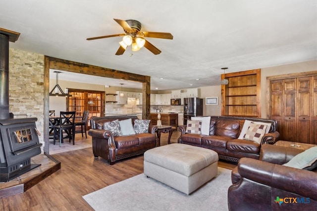 living room with hardwood / wood-style flooring, ceiling fan, and a wood stove