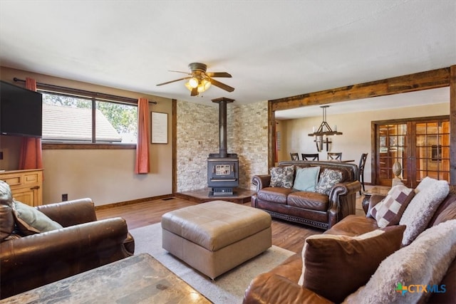 living room with light wood-type flooring, a wood stove, and ceiling fan