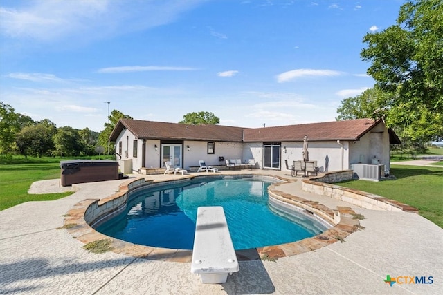 view of swimming pool with a patio, central air condition unit, a diving board, a yard, and a hot tub