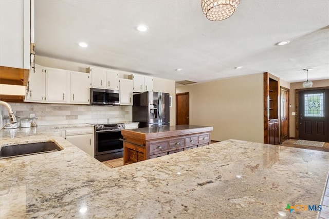 kitchen with sink, pendant lighting, decorative backsplash, white cabinets, and appliances with stainless steel finishes