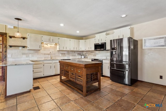 kitchen featuring pendant lighting, stainless steel appliances, white cabinetry, and tasteful backsplash