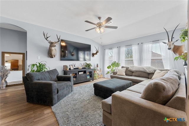 living room featuring lofted ceiling, wood finished floors, arched walkways, and ceiling fan