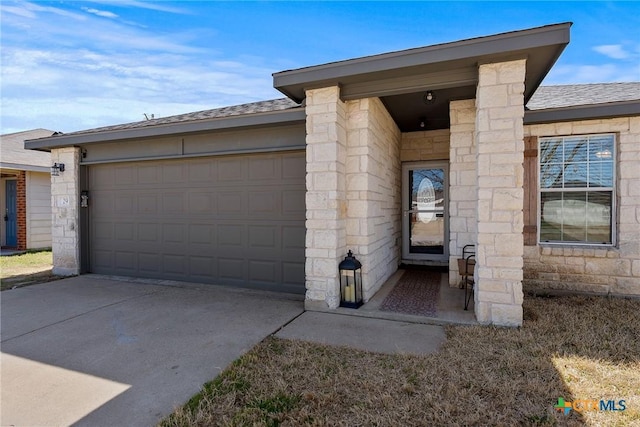 property entrance featuring concrete driveway, an attached garage, stone siding, and roof with shingles