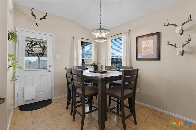 dining room with light tile patterned floors, baseboards, and vaulted ceiling