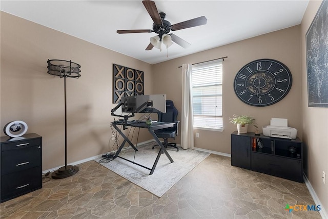 office area featuring baseboards, ceiling fan, and stone finish floor