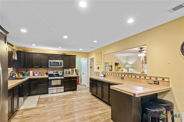 501 Hathaway St, Victoria, TX 77904 - kitchen featuring appliances with stainless steel finishes, a peninsula, backsplash, a kitchen bar, and recessed lighting