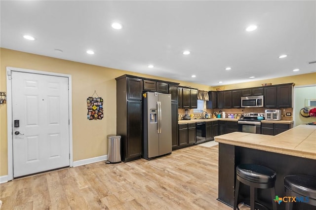 501 Hathaway St, Victoria, TX 77904 - kitchen with appliances with stainless steel finishes, tile countertops, light wood finished floors, dark brown cabinets, and recessed lighting
