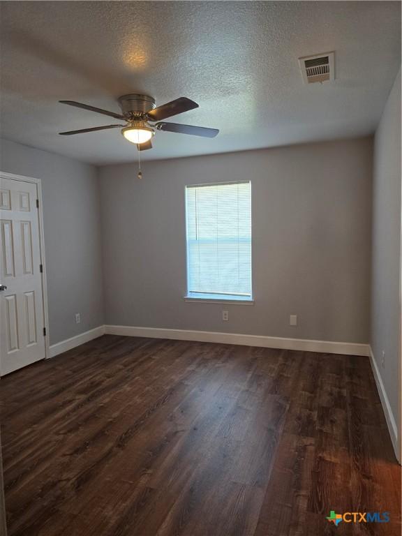 unfurnished room with a textured ceiling, dark hardwood / wood-style flooring, and ceiling fan