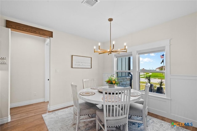 dining room featuring baseboards, light wood finished floors, visible vents, and an inviting chandelier