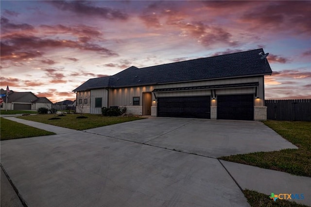 view of front of home with driveway, a garage, stone siding, a front lawn, and board and batten siding