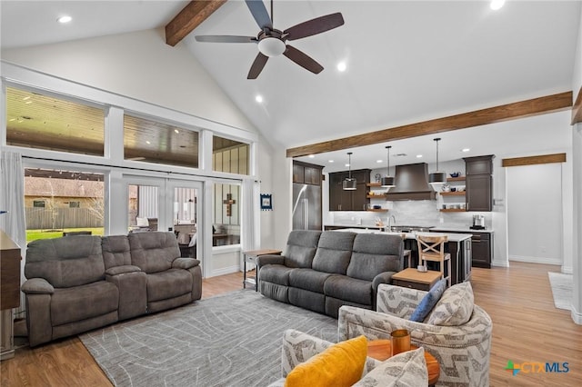 living room with light wood-style floors, ceiling fan, high vaulted ceiling, beamed ceiling, and baseboards