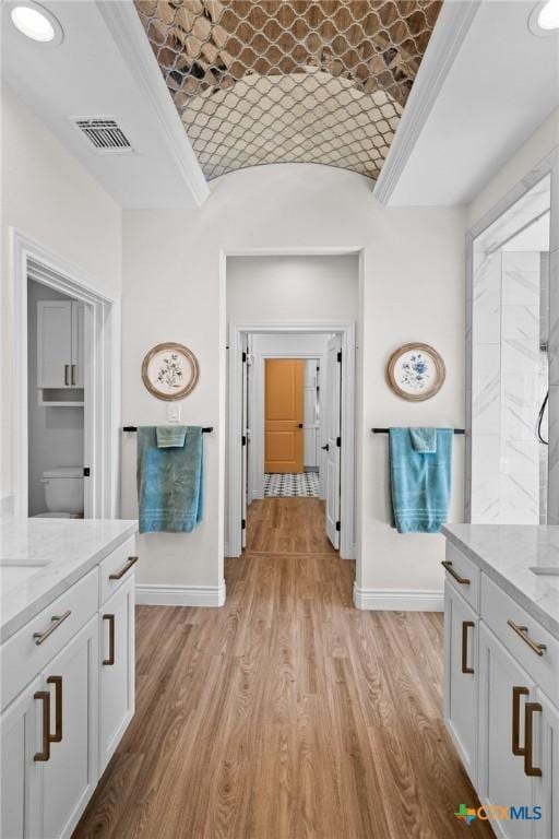 full bath featuring visible vents, vanity, wood finished floors, brick ceiling, and baseboards