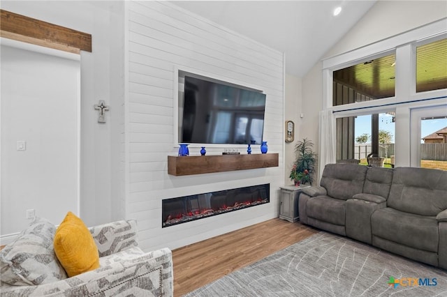 living room with lofted ceiling, a glass covered fireplace, recessed lighting, and wood finished floors