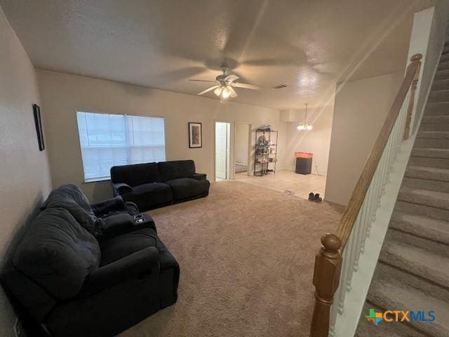 carpeted living room with ceiling fan with notable chandelier