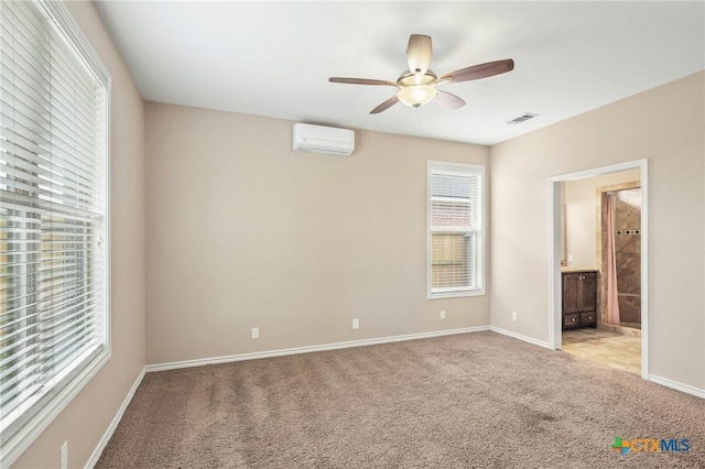 unfurnished bedroom with ceiling fan, light colored carpet, an AC wall unit, and connected bathroom