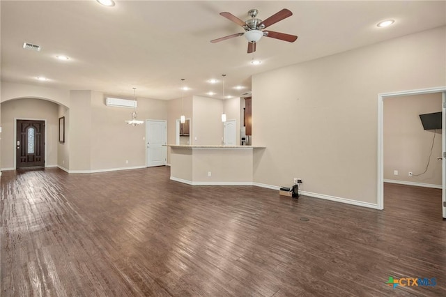 unfurnished living room with an AC wall unit, ceiling fan, and dark wood-type flooring