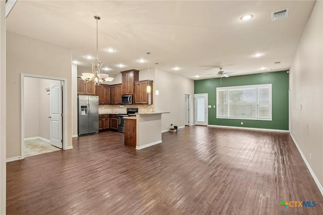 kitchen with kitchen peninsula, ceiling fan with notable chandelier, stainless steel appliances, dark wood-type flooring, and hanging light fixtures