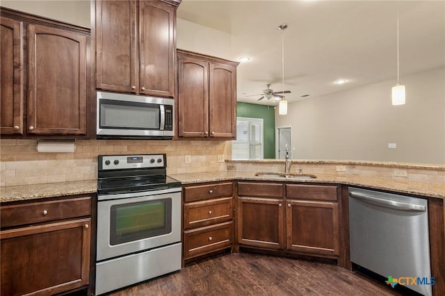 kitchen featuring light stone countertops, dark hardwood / wood-style flooring, stainless steel appliances, sink, and pendant lighting