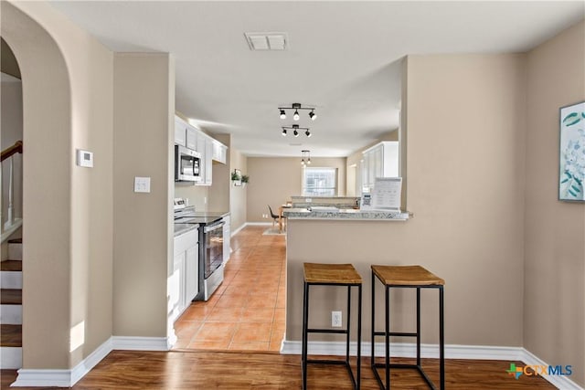 229 Rocky Ridge Dr, New Braunfels, TX 78130 - kitchen with stainless steel appliances, white cabinetry, a peninsula, a breakfast bar, and baseboards