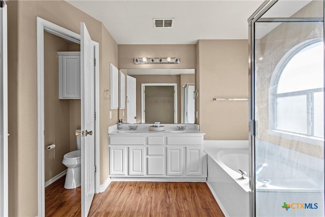 229 Rocky Ridge Dr, New Braunfels, TX 78130 - bathroom with wood finished floors, toilet, a garden tub, a shower stall, and double vanity