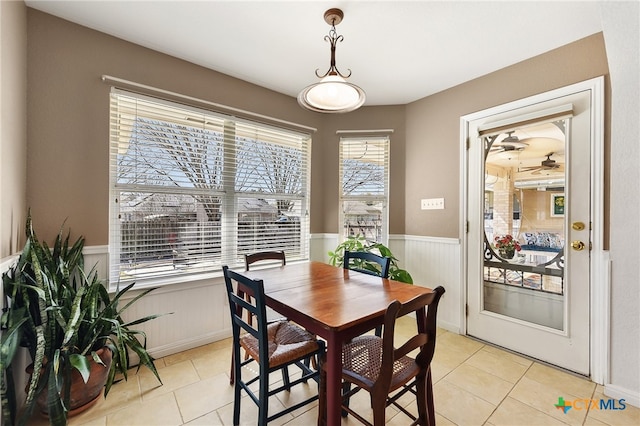 dining area with light tile patterned flooring and a wainscoted wall