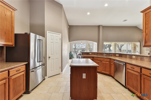 kitchen featuring a wealth of natural light, arched walkways, appliances with stainless steel finishes, and a sink